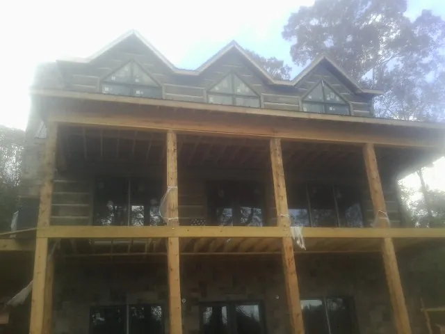 Dormers and porch framing on a large log home under construction — Roof Coating work by our crew in Saint Albans